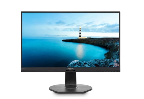 Philips computer monitor displaying a scenic coastal landscape with a lighthouse on a rocky cliff overlooking blue ocean waters at dusk