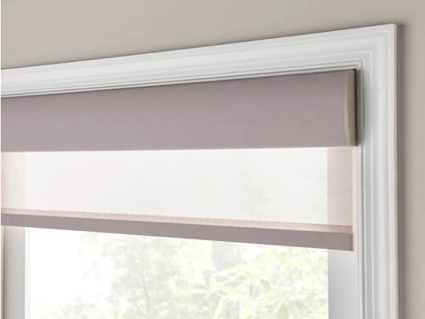 Close-up of a roller shade with taupe and white horizontal stripes installed on a white-framed window