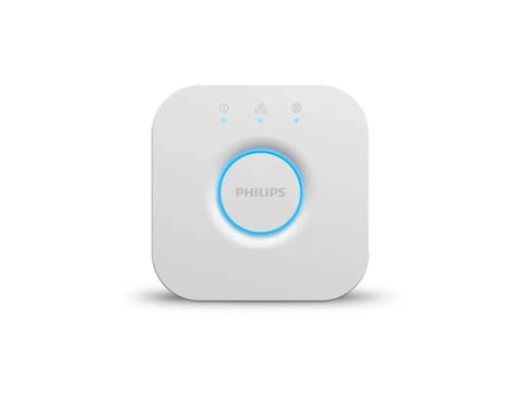 Philips Hue Bridge smart home hub with blue illuminated button and control icons on white square device
