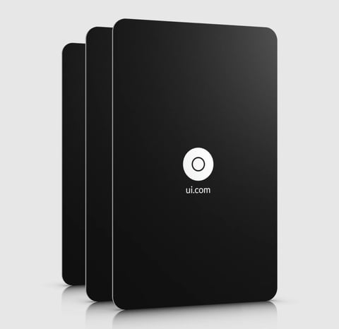 Three stacked black tablet devices with rounded corners and a circular logo with ui.com text displayed on the front screen