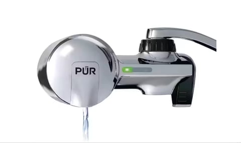 PUR tap water filter mounted on faucet with water stream flowing from the filter cartridge